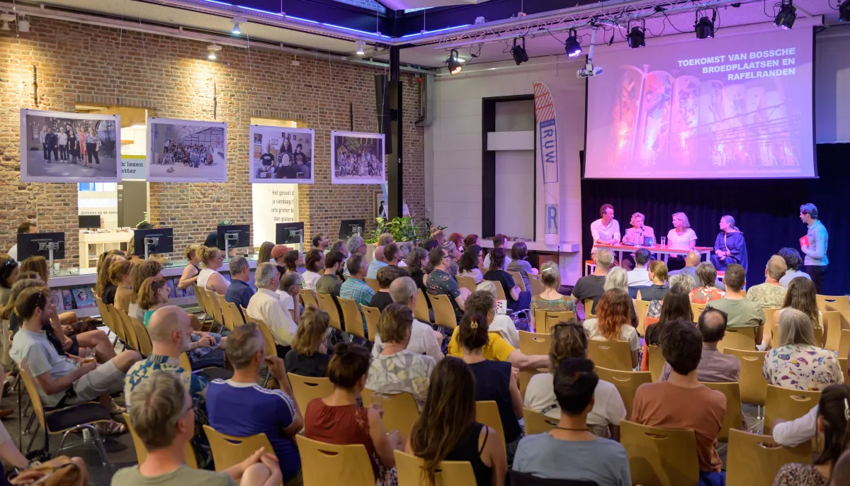 Een zaal vol publiek volgt het gesprek bij RUW
