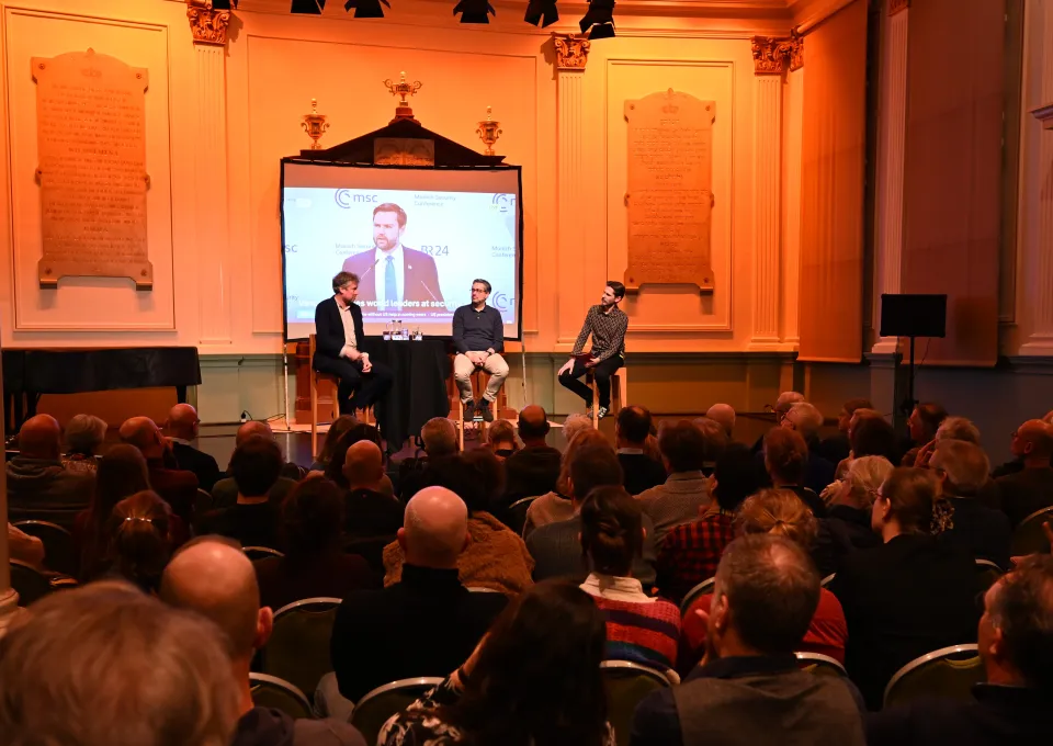Een programma met bezoekers, met drie mensen op een podium 