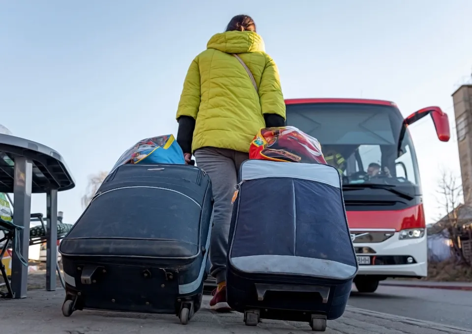 Een vrouw met koffers loopt naar een bus