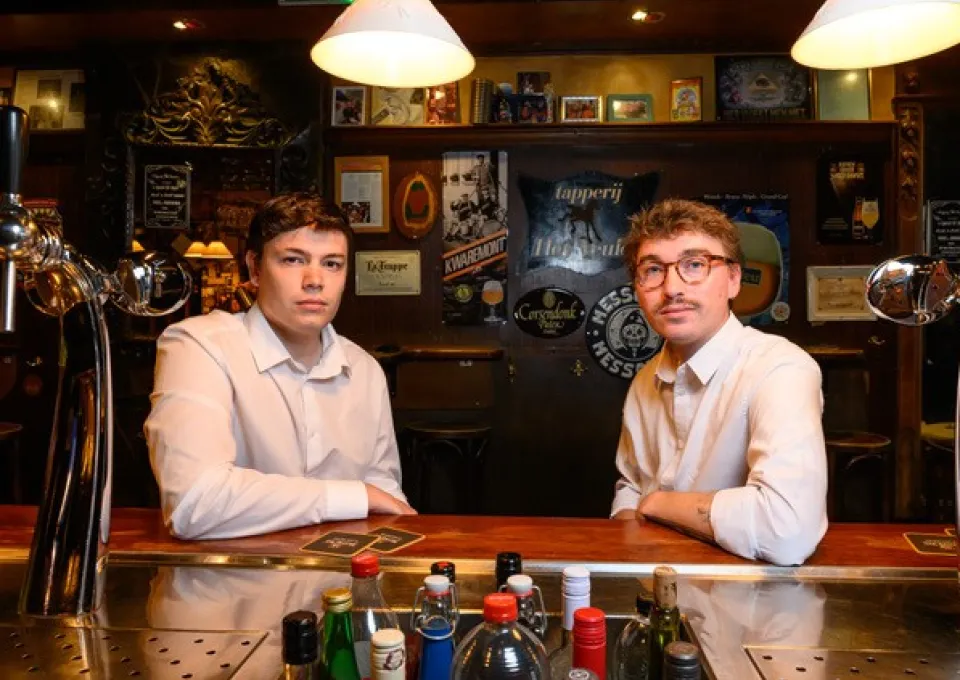 Twee jonge mannen in witte overhemden in een bruine kroeg