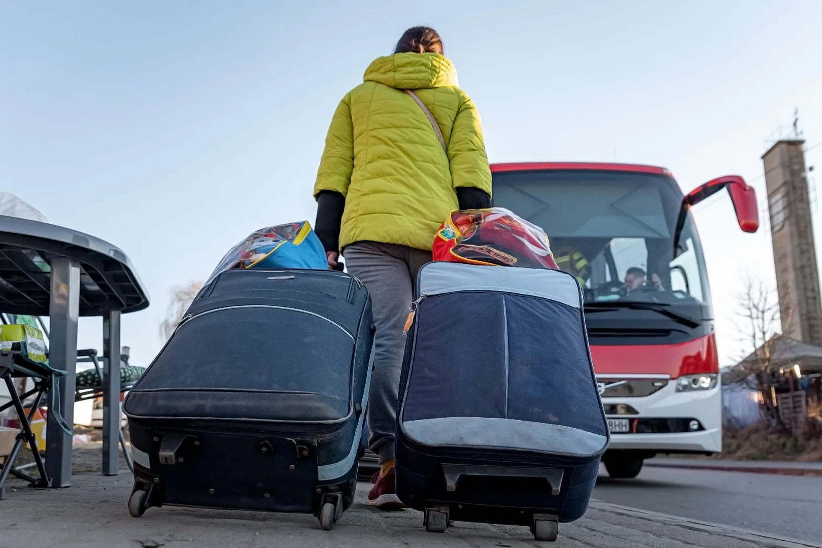 Een vrouw met koffers loopt naar een bus