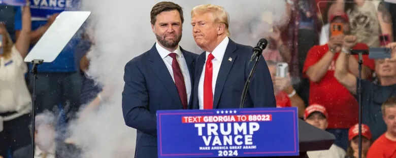 Donald Trump en JD Vance die elkaar de hand schudden.