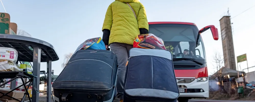 Een vrouw met koffers loopt naar een bus