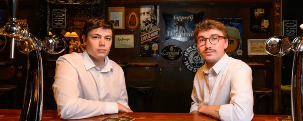Twee jonge mannen in witte overhemden in een bruine kroeg