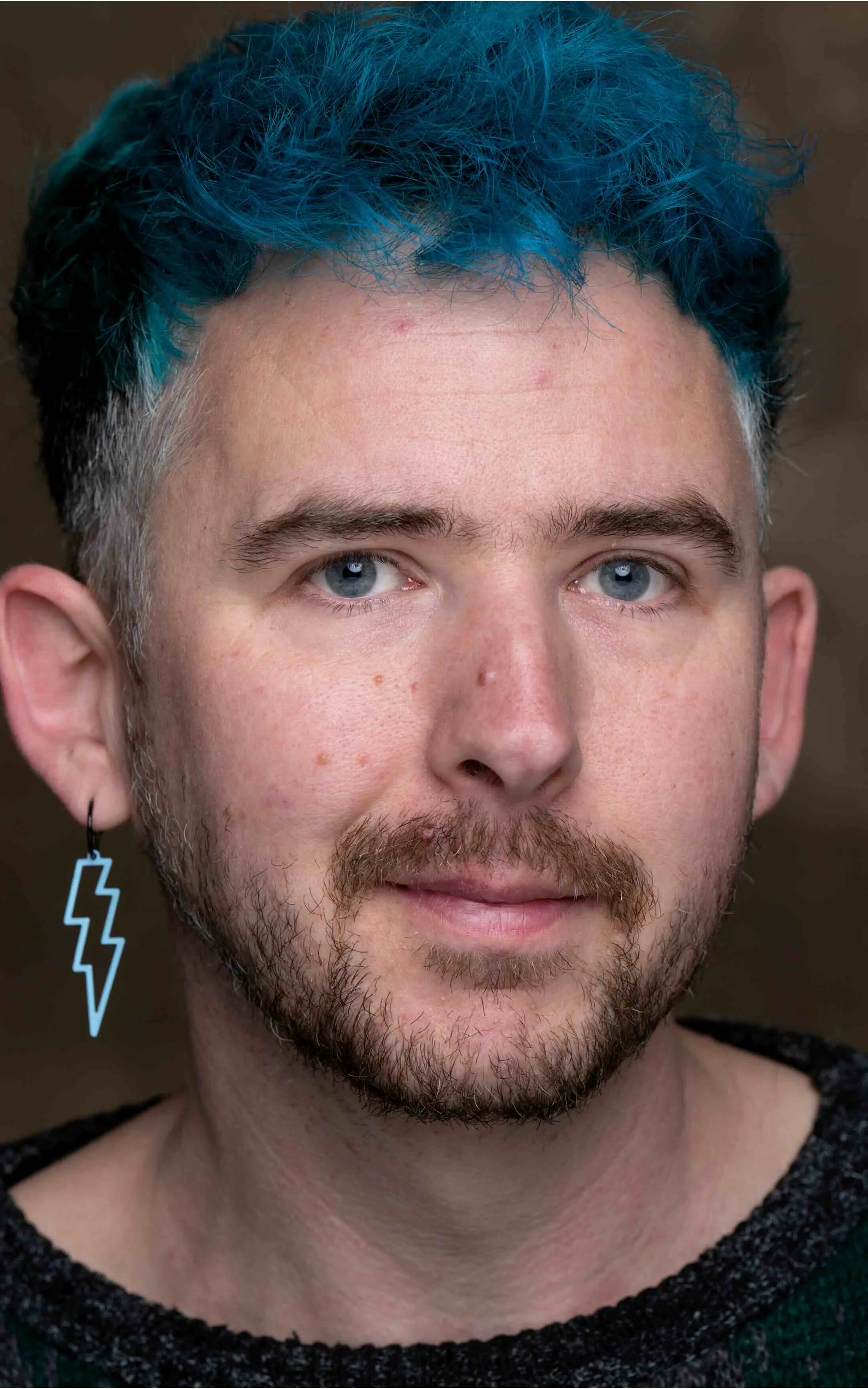 Man met blauw haar en bliksemschicht oorbel