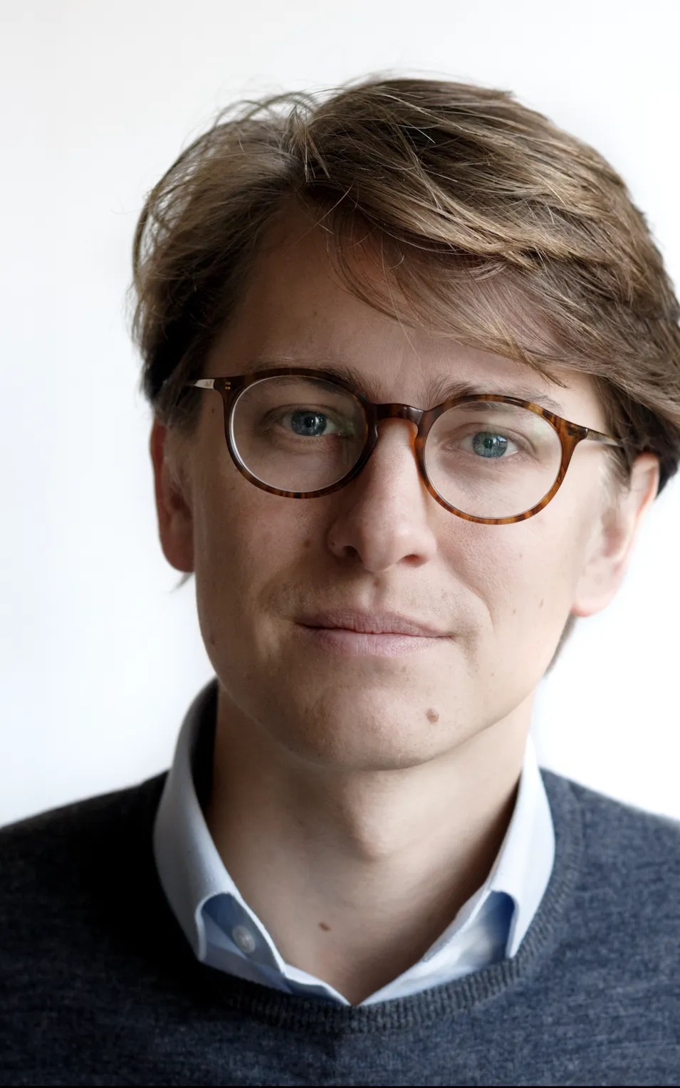 Jonge man met bril, bruin haar en boord onder zijn trui